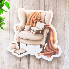 Maxi samolepka zobrazuje pohodlné křeslo, přes které je přehozená hřejivá deka. Na křesle leží otevřená kniha a vedle ní šálek kávy. Tento motiv vyzařuje klid a útulnost, ideální pro chvíle čtení a odpočinku.