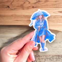 Maxi samolepka zobrazuje elegantní dívku v modrém kabátu a deštníkem, kráčející s jistotou, navzdory dešti. Její styl a sebedůvěra vyzařují z každého detailu, čímž samolepka přináší do každého diáře eleganci a odhodlání.